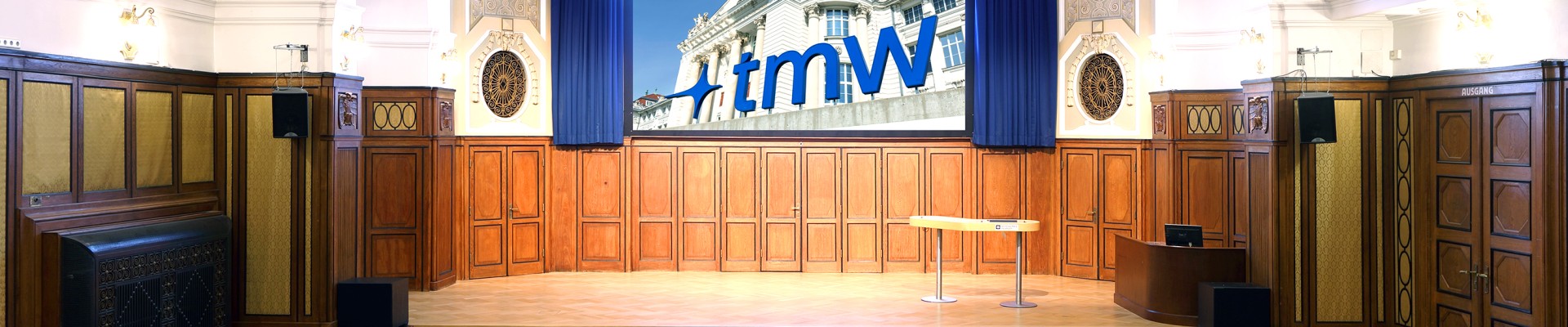 Banquet hall with stage, screen and rows of chairs at the Technisches Museum Wien: 