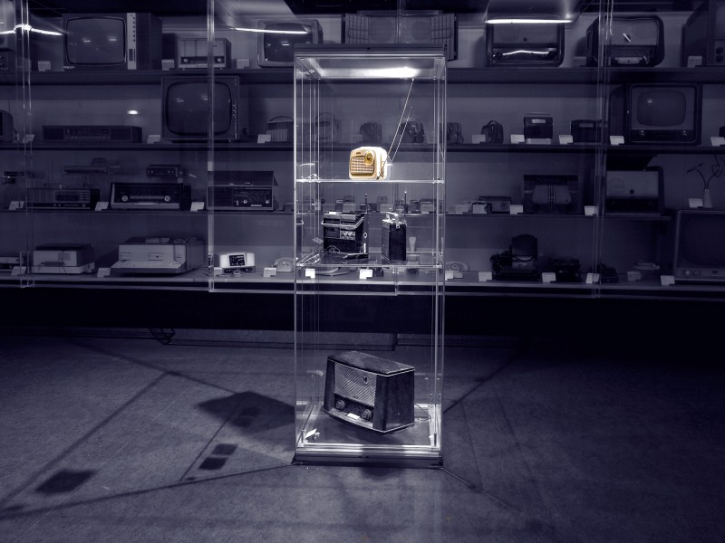 : Schwarz-weiß Foto von Glasschrank mit Objekt (gelbes Transistorradio)