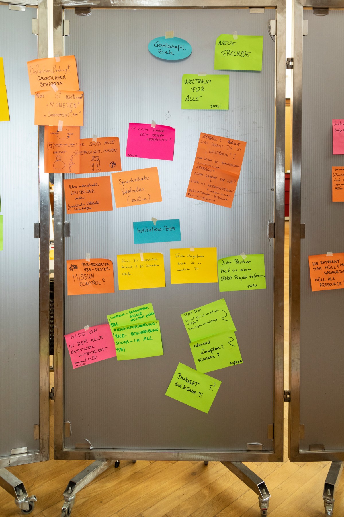 Tafel mit Post-its mit Ideensammlung mit gesellschaftlichen und institutionellen Zielen