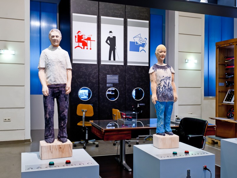 : Holzfiguren stehen auf den Hörstationen in der Ausstellung "In Arbeit" auf Ebene 3.