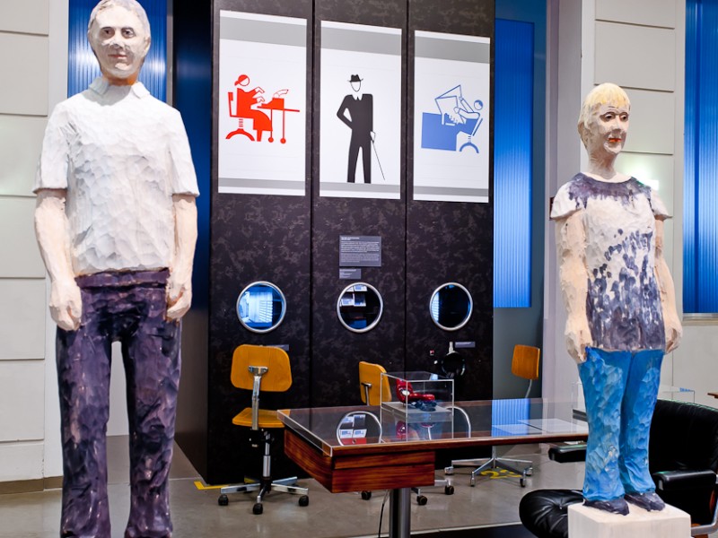 Wooden figures are standing on the listening stations in the exhibition "At Work" on level 3.: 