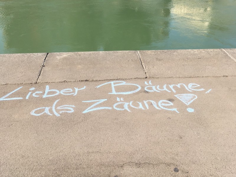 Wiener Donaukanal: Kreideschrift am Asphalt "Lieber Bäume als Zäune": 