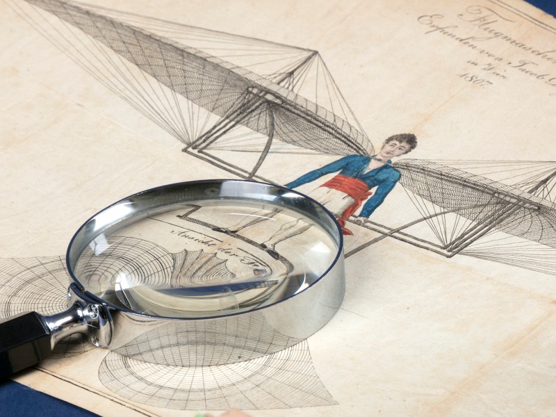 •	Lupe auf einer kolorierten Zeichnung einer Flugmaschine von Jakob Degen aus dem Jahr 1807: 