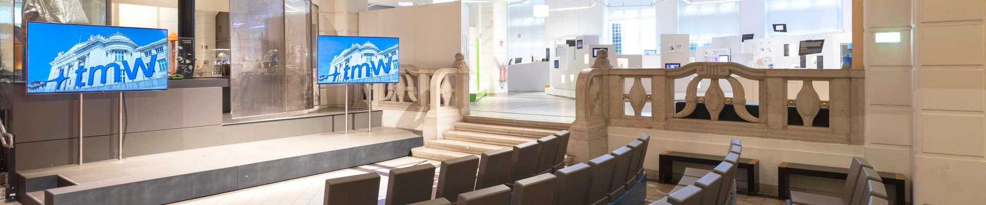 Presentation area with curved seating and a stage with two screens at the Technisches Museum Wien: 