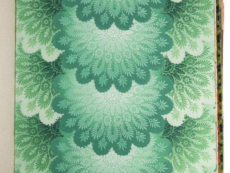 Gesamtaufnahme einer Musterbuchseite mit ornamentaler Buntpapiergestaltung in Grün- und Türkistönen. Das symmetrische Muster besteht aus stilisierten Blatt- und Farnmotiven, die sich in großen, fächerförmigen Formen über die gesamte Seite wiederholen: Abb. 4: Gesamtaufnahme der beprobten Seite eines „Buntpapier-Musterbuchs“ (Inv.-Nr. 61125)