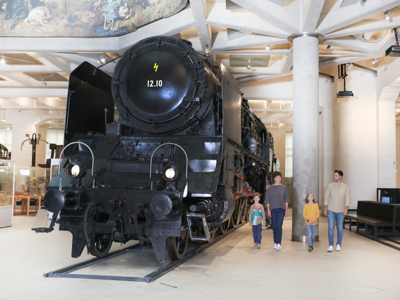 : Eine Familie sieht sich gemeinsam die 12.10er Dampflokomotive an. In der Ausstellung "12.10 eine Dampflokomotive der Superlative" 