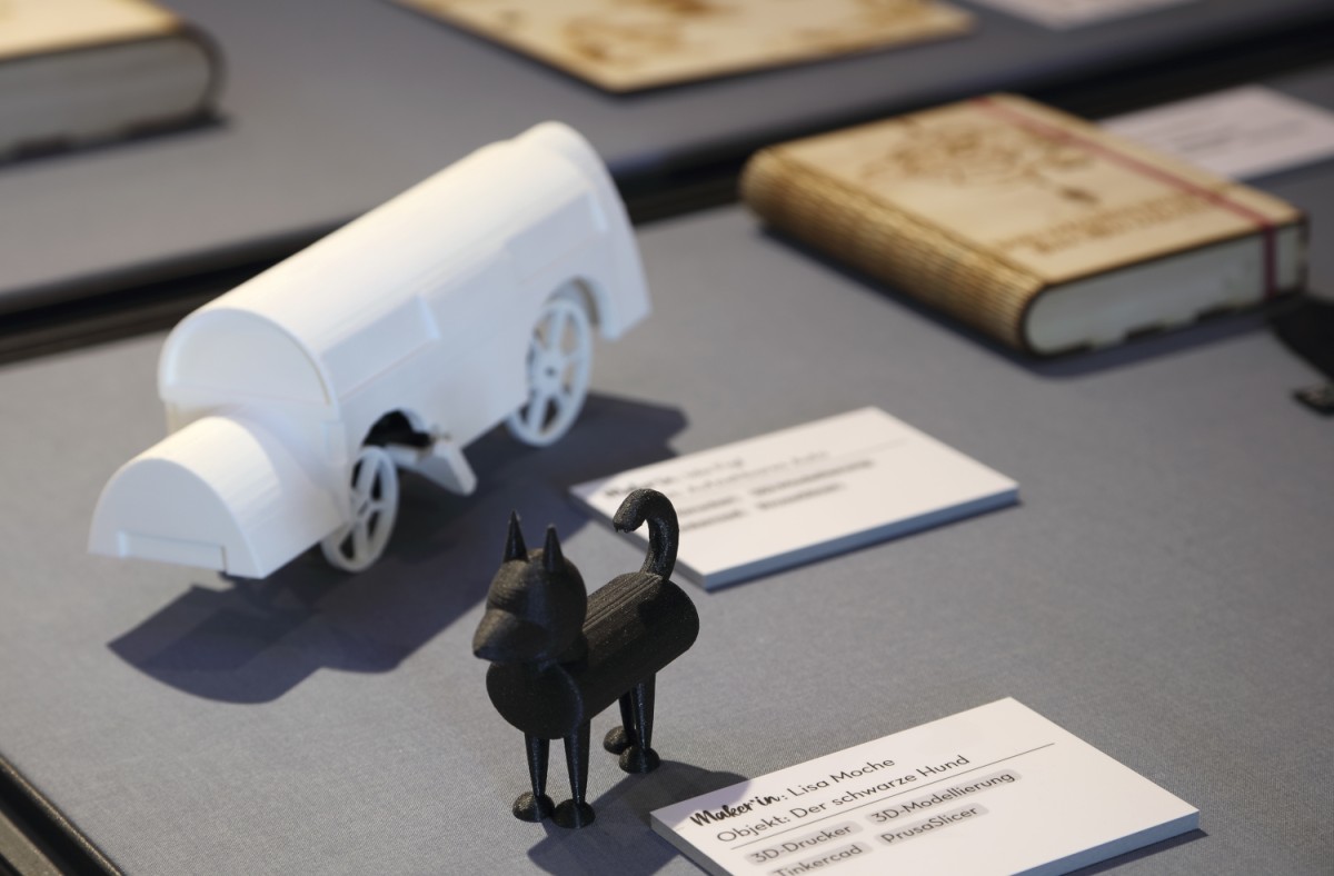 : Maker*Sisters Pop-up-Ausstellung (2020) mit einer Vielzahl selbst produzierter Objekte, im Bild: schwarzer Hund, selbstfahrendes Auto und Kompass-Buch