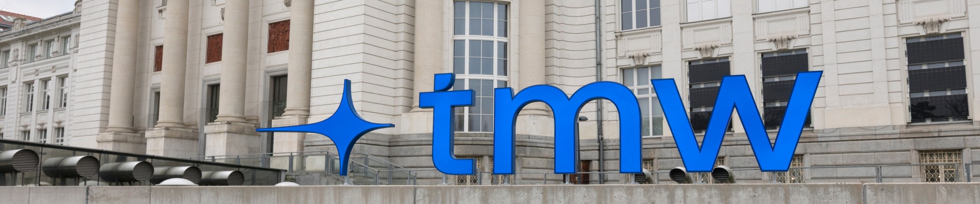 Vorderseite des Technischen Museums Wien mit neuem Logo, das aus den blauen Kleinbuchstaben T, M und W gebildet wird: Vorderseite des Technischen Museums Wien mit neuem Logo,