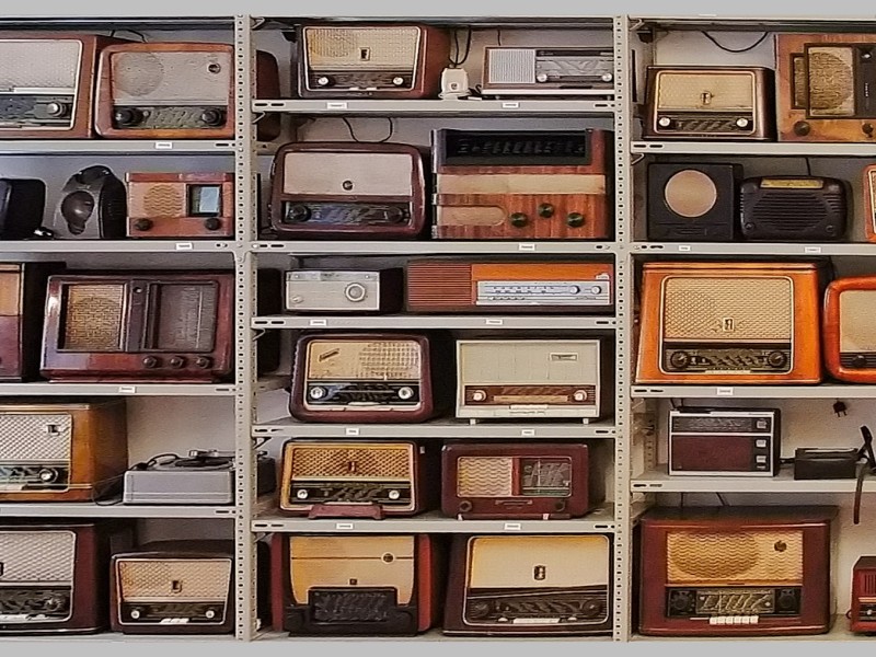 Regalwand mit zahlreichen historischen Radiogeräten aus verschiedenen Jahrzehnten: 