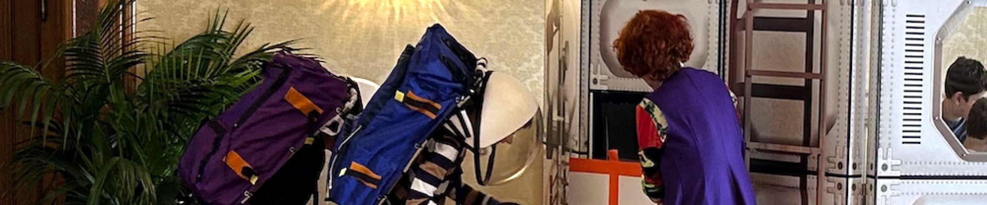Zwei Kinder in Astronautenkleidung erkunden eine weltraumähnliche Station: EVA-Astronaut:innen sammeln Gesteinsproben, die sie zu weiteren Untersuchungen in die Glove-Box legen.