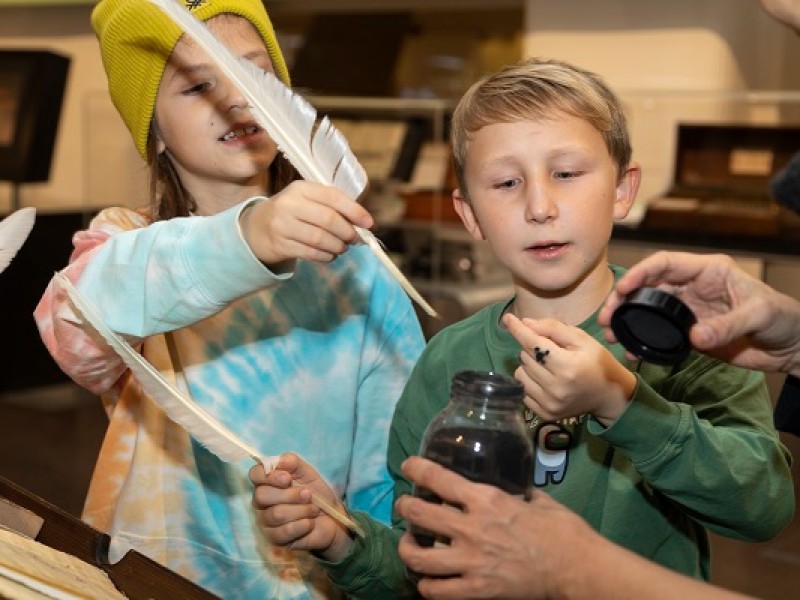 Kinder probieren Federn und Pigmente während eines Workshops aus