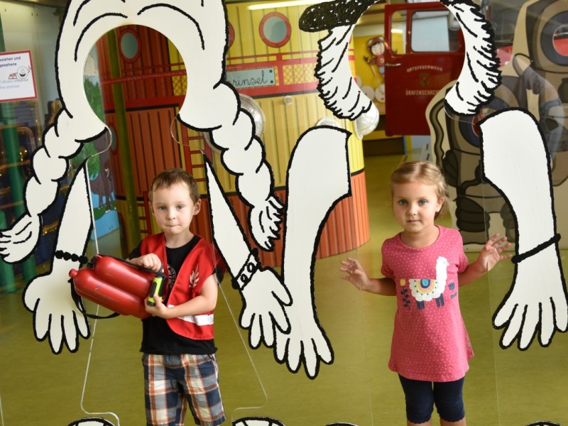 Children look through punched-out paper shapes in the "Mini" experience area: 