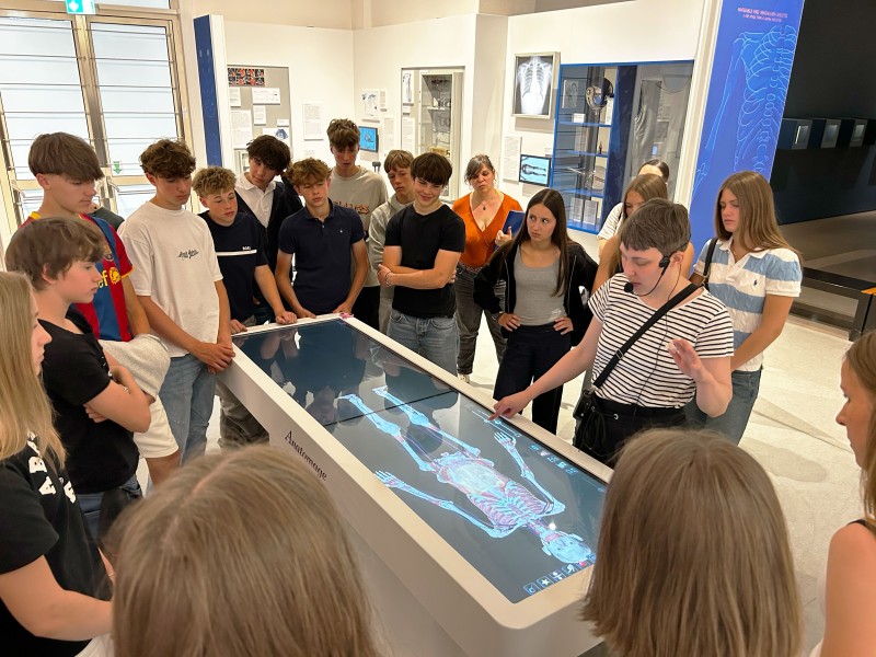 Eine Gruppe von Schülern untersucht einen Körper beim Anatomage-Tisch im Technischen Museum Wien. : 