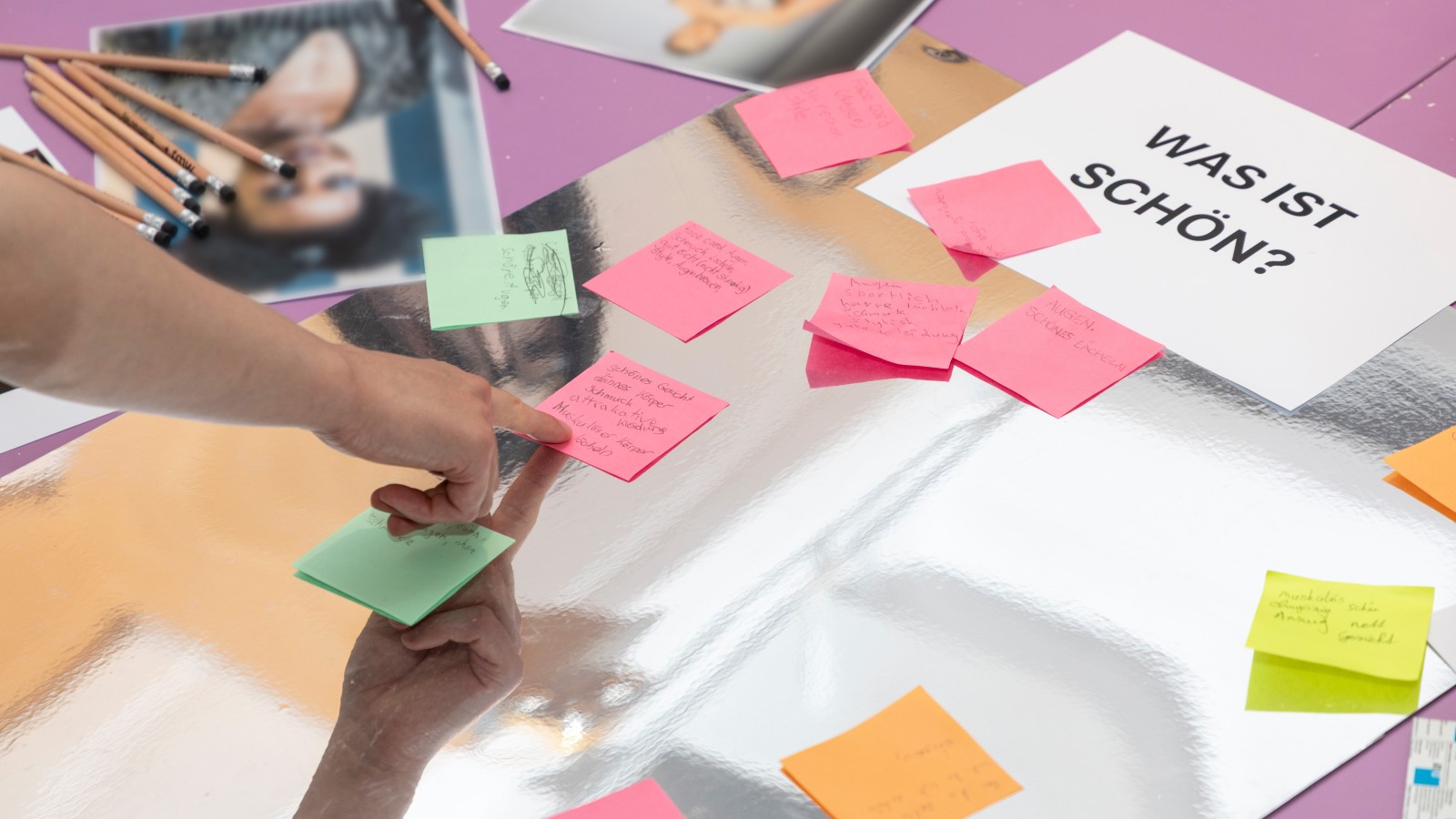Teilnehmer setzen Post-It-Notizen auf Plakate mit Fragen zum Thema Körperbild und Stressbewältigung.: