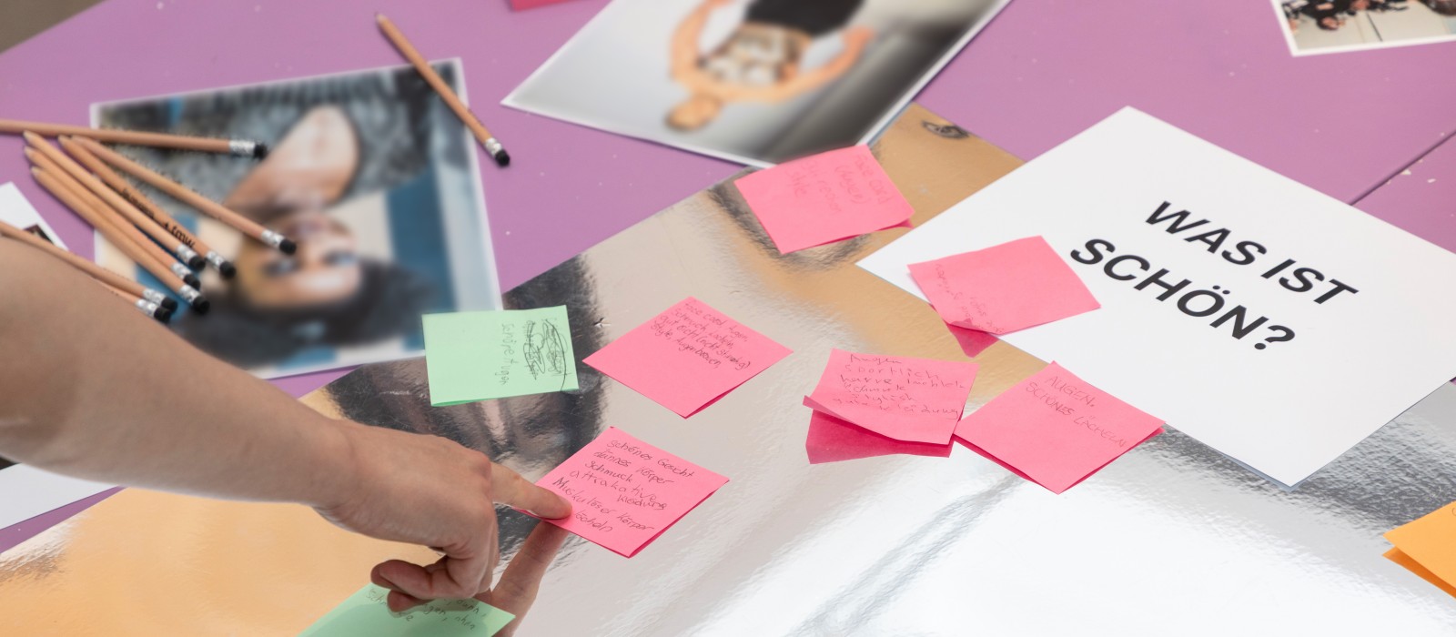 Teilnehmer setzen Post-It-Notizen auf Plakate mit Fragen zum Thema Körperbild und Stressbewältigung.: