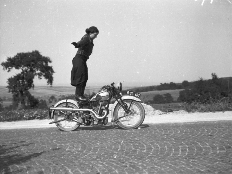 Ein Schwarz-Weiß-Foto von Anny Deim auf einem fahrenden Motorrad: Anny Deim: Kunstfahren am Motorrad, 1935

