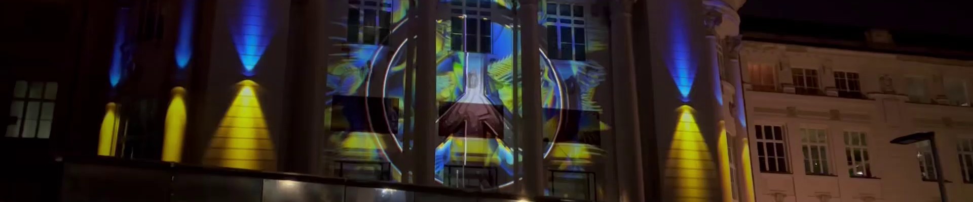 : Beleuchtung der TMW-Fassade mit ukrainischer Fahne und Friedenszeichen