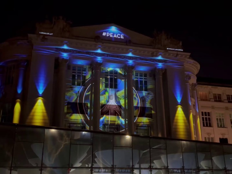: Beleuchtung der TMW-Fassade mit ukrainischer Fahne und Friedenszeichen