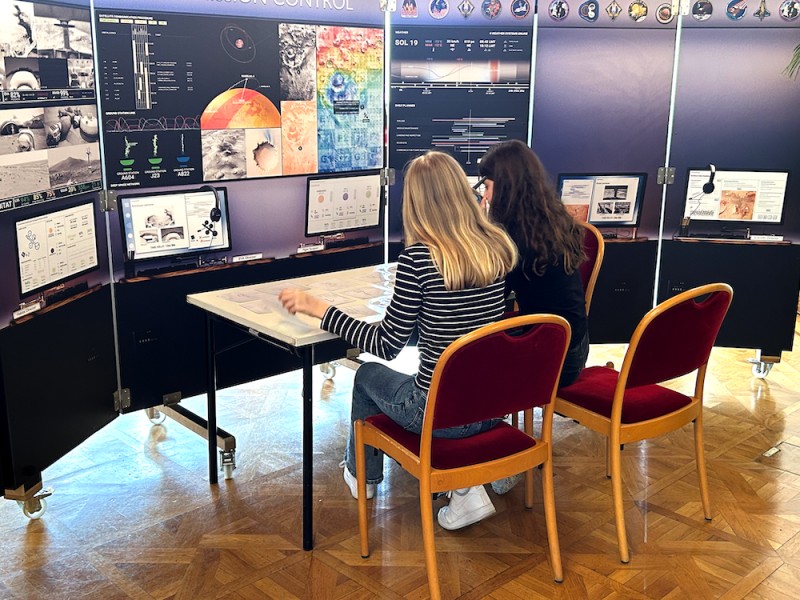 Zwei Mädchen erkunden die interaktive Raumfahrtstation beim Forschungsfest:  Die Mission Control auf der Erde berät darüber, welches Alien wohl auf dem Mars gesichtet wurde.