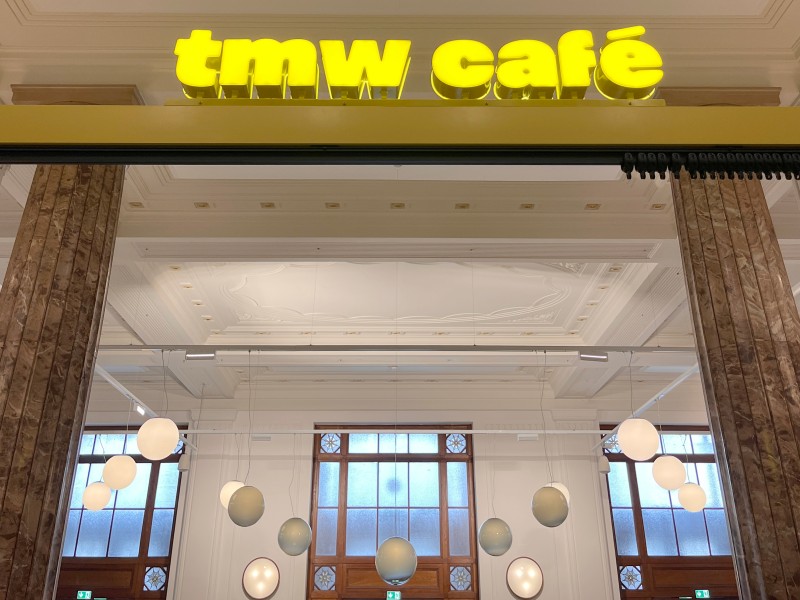 Illuminated yellow sign “tmw café” at the entrance of the café at the Technisches Museum Wien: 