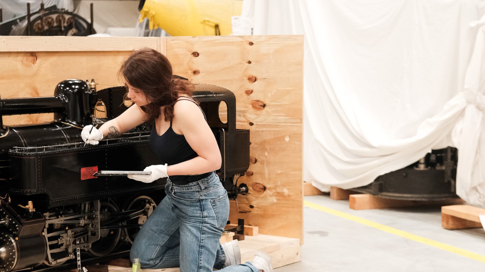 Restauratorin arbeitet sorgfältig an einem historischen Eisenbahnmodell in der Ausstellung ‚Im Bann der Bahn‘.“: 