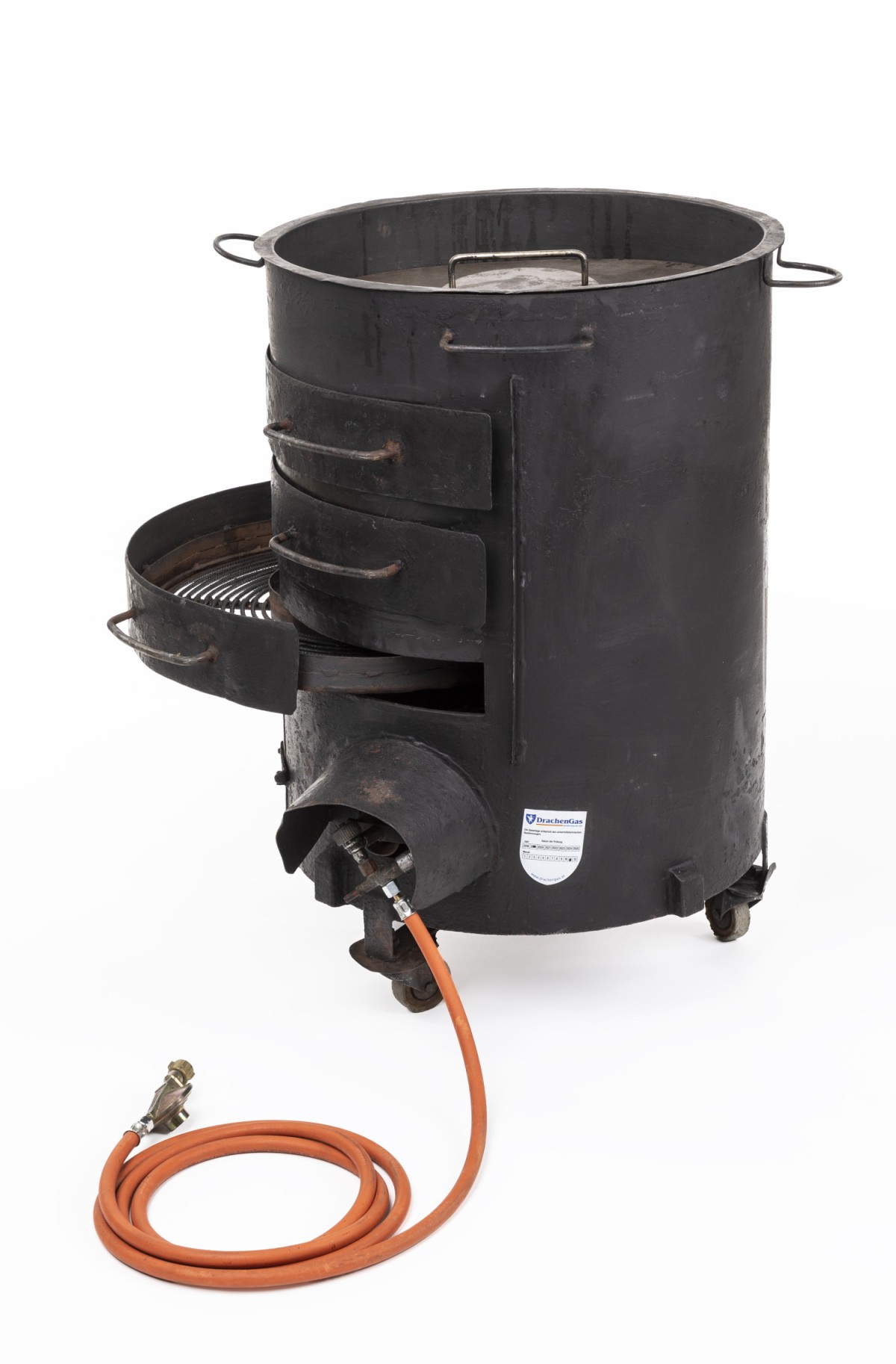 Schwarzer, zylindrischer Gasmaroniofen mit seitlich ausgeklapptem Rost, Rollen und orangefarbener Gasleitung: Maroniofen für Befeuerung mit Gas, 2010 (Inv.-Nr. 113399)