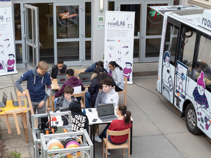 Das roadLab parkt vor einer Schule: Der roadLAB E-Bus parkt vor der Bildungseinrichtung und die Schüler_innen tüfteln und designen direkt vor der mobilen Werkstatt.