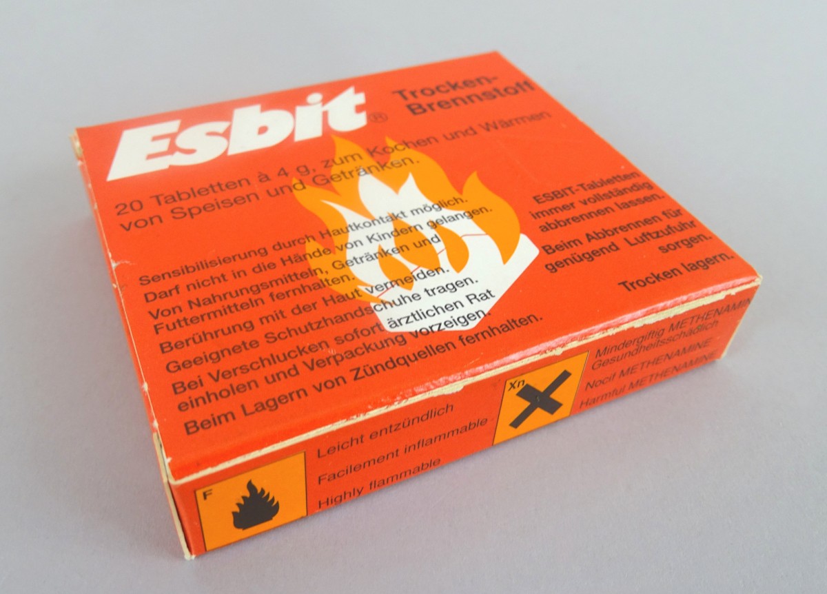 Orangefarbene ESBIT-Box mit Flammen-Logo und Sicherheitshinweisen: Trockenbrennstoff der Marke „Esbit“ für Experimentierbox „Luft“