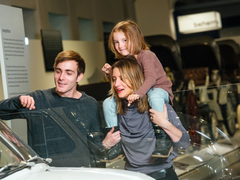 Eine Familie sieht sich in der Ausstellung "Mobilität" ein Auto an: 
