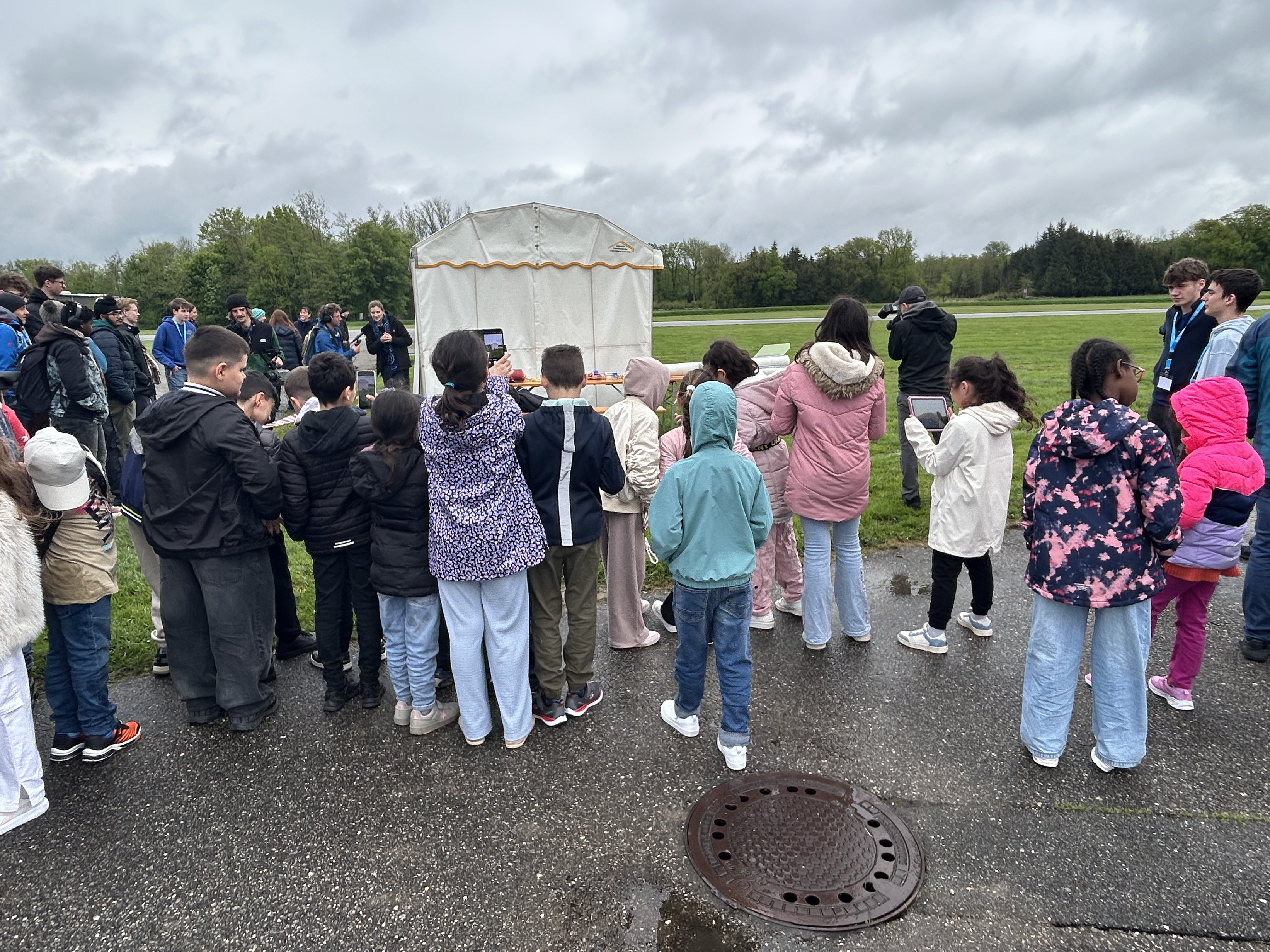 The students are eagerly waiting for the launch to begin. Smartphones and tablets are already ready to capture the rocket launch!