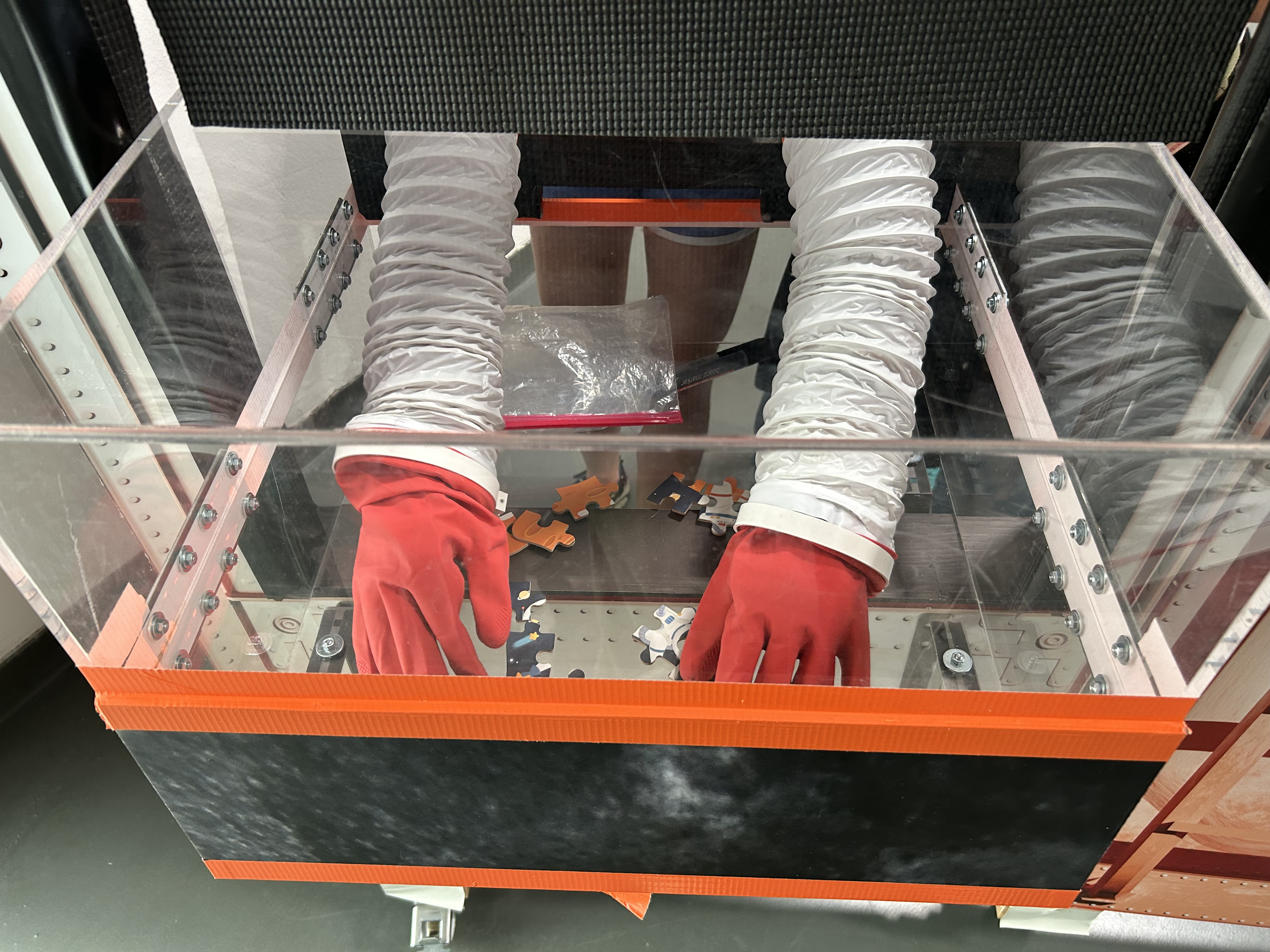 Handle with care! Bei der Entgegenahme von außerirdischen Gesteinsproben ist in der Glove Box äußerste Vorsicht gefragt, daher sind Handschuhe ein Muss.